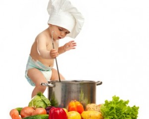 Little boy in chef's hat with ladle, casserole, and vegetables